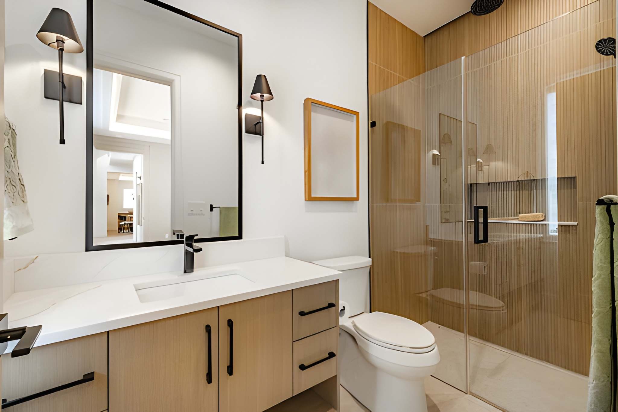 Modern bathroom remodel in Palm City featuring wood vanity, black fixtures, and glass shower enclosure