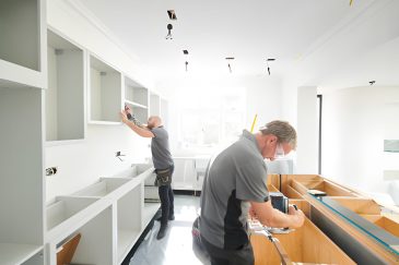 Kitchen remodeling West Palm Beach FL team installing custom cabinets in sunlit modern home