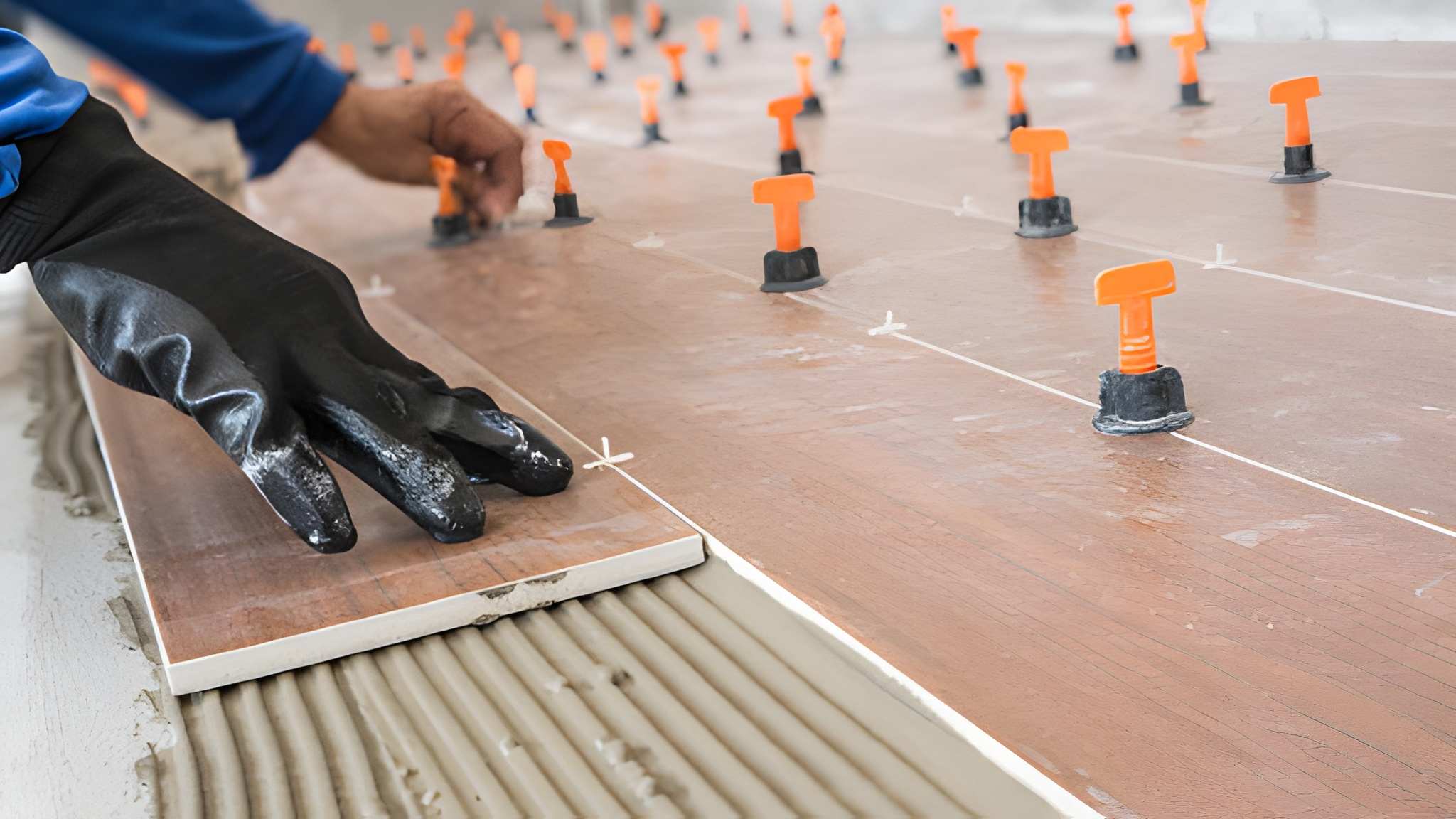 Tile installer placing ceramic floor tile with leveling spacers—Tile and Marble of Palm Beach