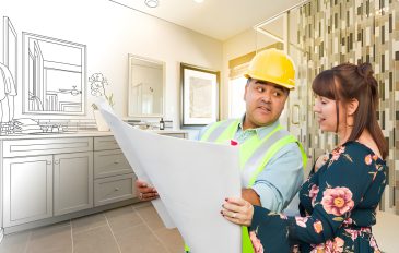 Bathroom remodel contractors near me in Jupiter FL—worker reviews blueprint with homeowner in partially finished bathroom.