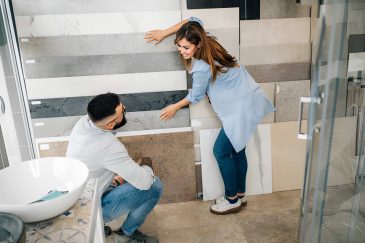 Tile stores near me—customers examining large wall-mounted tile samples in showroom.